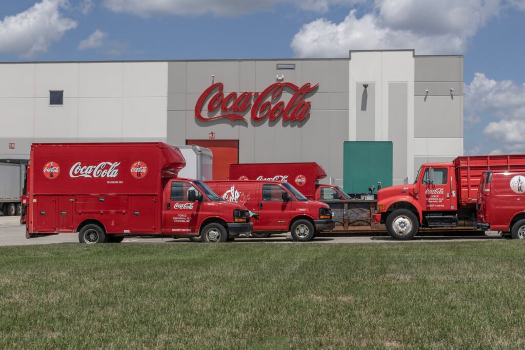 Coca-Cola plant with delivery trucks in front, illustrating value-based pricing and consumer perception in different markets.
